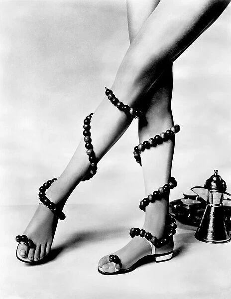 Woman wearing unusual pair of shoes with beads wrapped around her legs