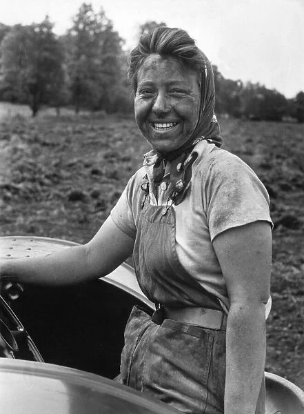 A woman at work cultivating rich black farmland soil in the English countryside