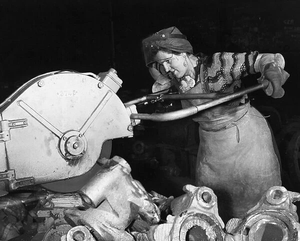 Woman worker using heavy machinery in a metal factory April 1956