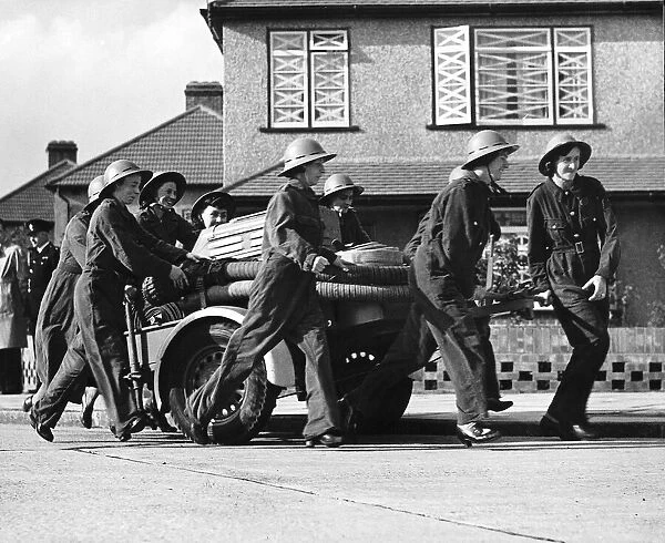 Women fire fighters from Erith Kent walk beside their trailer pump during WW2 1942