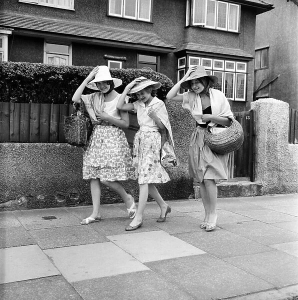 Three women hold on to their hats on the seafront at Haylake. June 1960 M4313-003