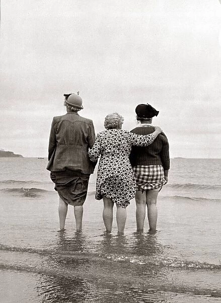 Three women look out to sea watching a ship disappear over the horizon clutching the hems
