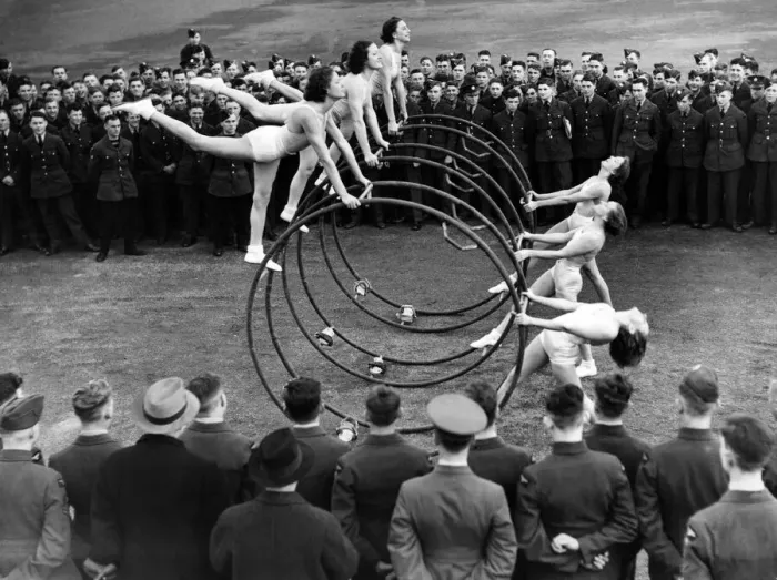 Framed Print : Women performing a gymnastic routine with large metal hoops, watched by military men Framed Print : Women performing a gymnastic routine with large metal hoops, watched by military men