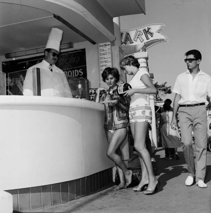 Framed Print : Women queue up to buy a drink from the snack bar on the beach during a holiday Framed Print : Women queue up to buy a drink from the snack bar on the beach during a holiday