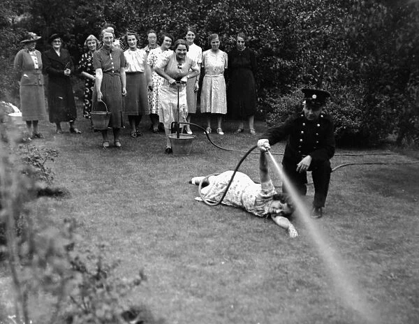 Women in Royden Grove, Lincoln Receiving Instruction in the use of a stirrup pump to put