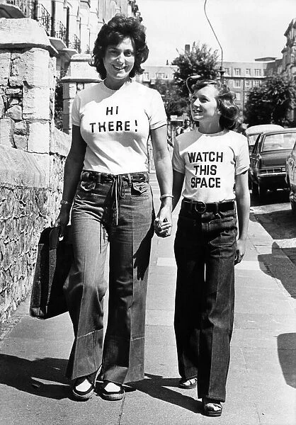 Women walking down the street wearing t shirts with amusing slogans August 1976