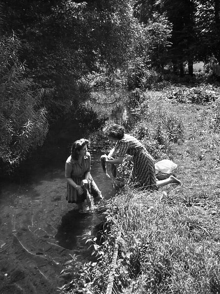 Two women washing their clothes in the River Chess at Broadwater Bridge near Chesham
