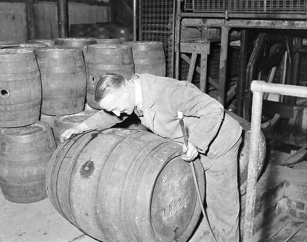 Workman rolling a barrel of ale at Ansells Brewery, September 1957