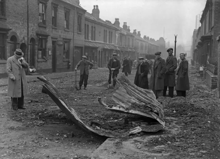 Framed Print : Workmen inspect the remains of a Anderson shelter that was blown over the rooftops into Framed Print : Workmen inspect the remains of a Anderson shelter that was blown over the rooftops into