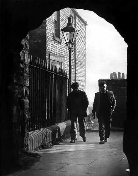 Workmen on their way from the quayside pass through the arch at the head of the Castle