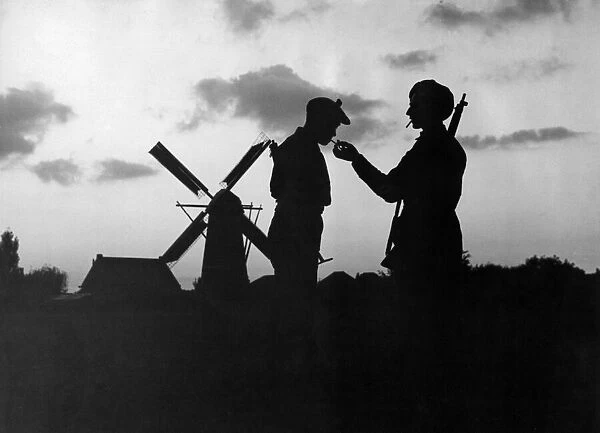 World War Two. 'Eventide in Holland'. British Soldiers pause to light their