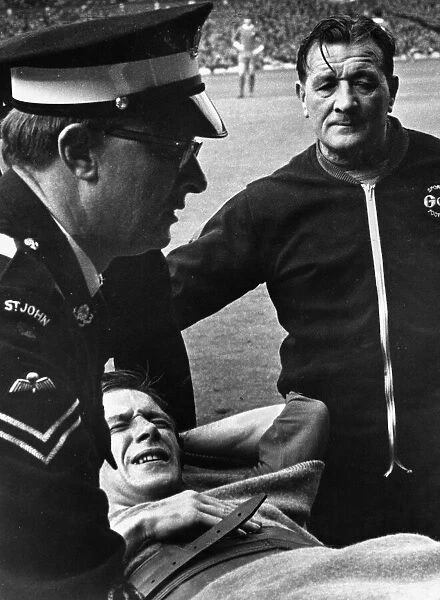 Worried looking Liverpool trainer Bob paisley looks on as Bobby Graham is carried off