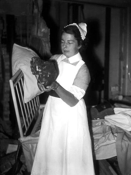 WW2 Air Raid Damage A nurse holds up a large stone in a hospital ward after
