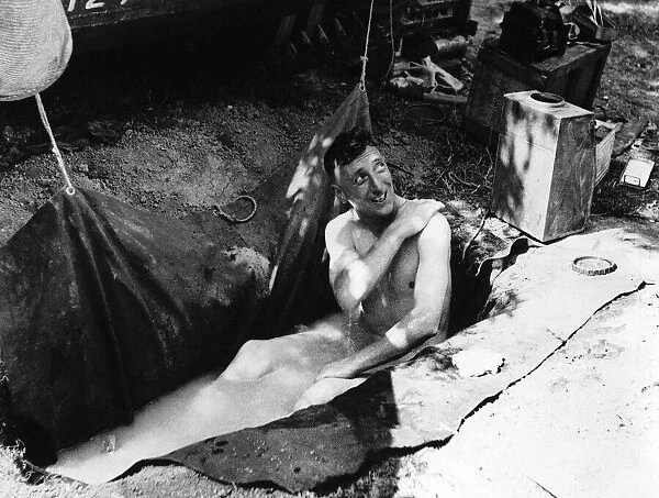 WW2 Corporal W Noble of Northampton taking a bath in a groundsheet placed in a slit