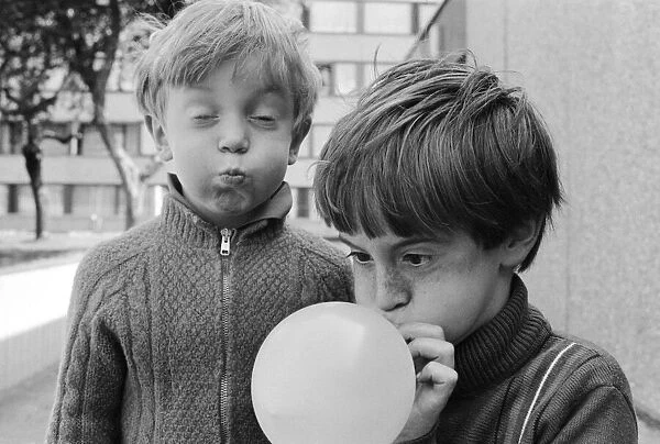 Eight year old Joseph Clifford of Hackney blows up his balloon as his younger brother