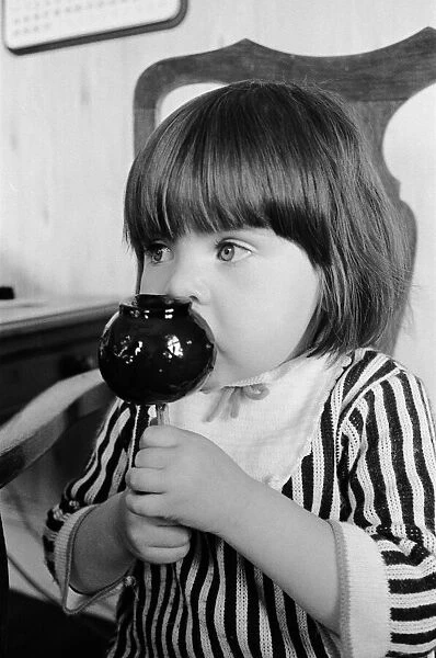 Two year old Tracey Emmanuel of Wembley, London, samples an old English toffee apple at