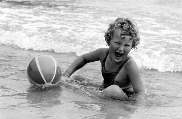 Yound girl playing with her beach ball during a holiday at the seaside Circa 1945