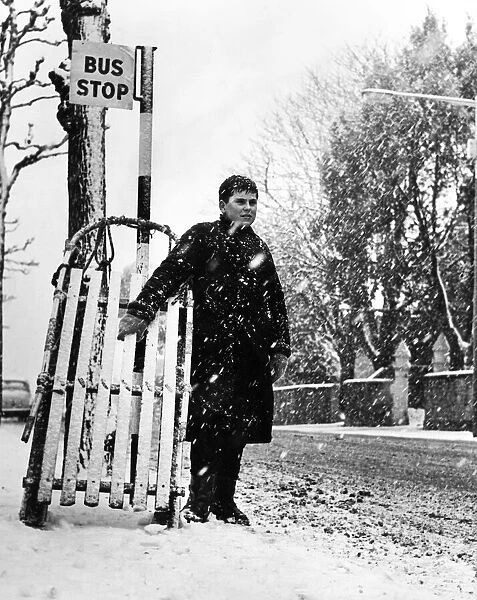 Young Andrew Burley stands in the queue for the bus with his sledge during heavy snowfall