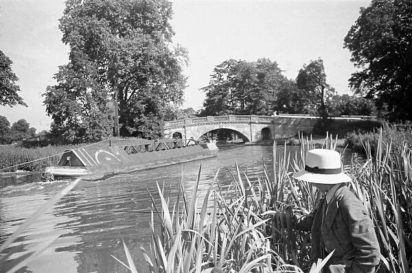 A young angler wearing a panama hat fishing in the Grand Union Canal between