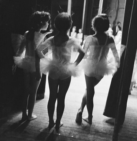Three young ballerinas look on at the performance of Sleeping Beauty from the wings of