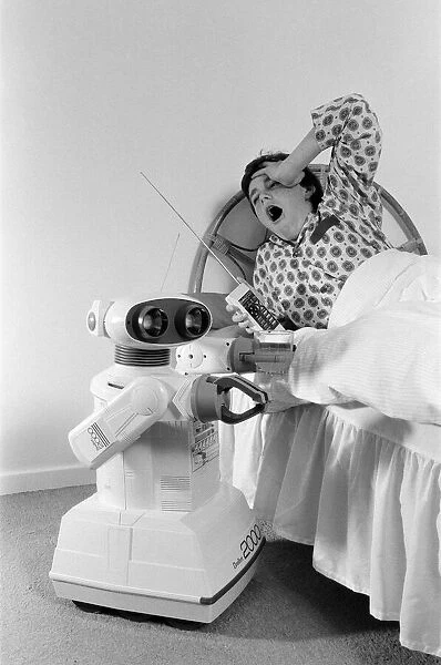 A young boy in bed being woken by an Omnibot 2000 toy robot. 21st October 1986
