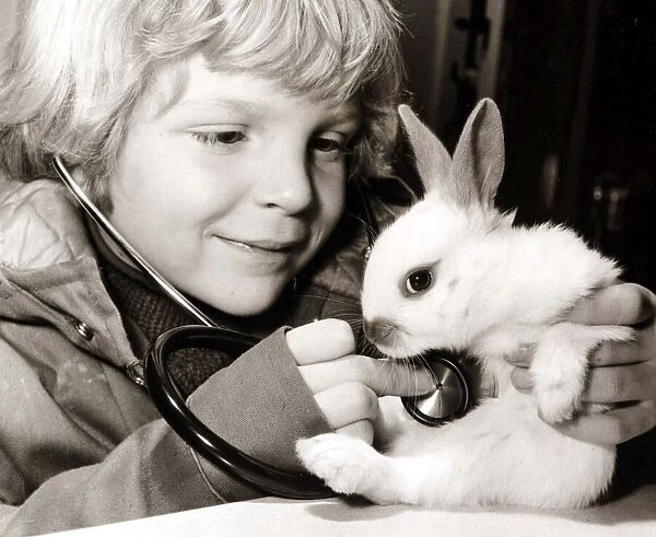 A young boy examines his rabbit, using a stethoscope to listen for a heartbeat