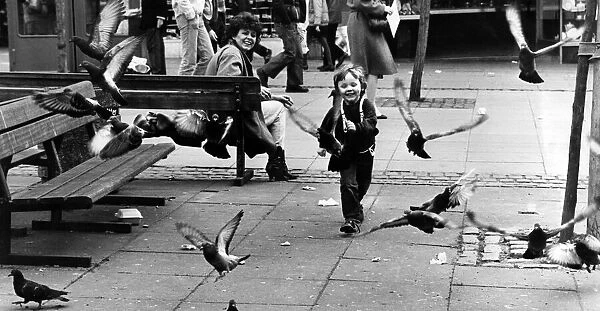 A young boy having fun chasing pigeons, Liverpool. 13th April 1984