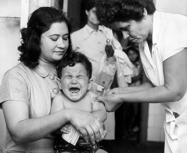 Young boy held closely by his mother, screams as the nurses gives him a vaccination