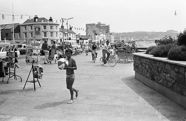 A young boy holding his beach at the seafront in St Helier on the Channel Island of