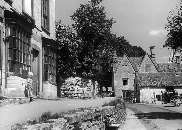 Young boy peering theough a shop window in the Cotswold village of Uley near Dursley in