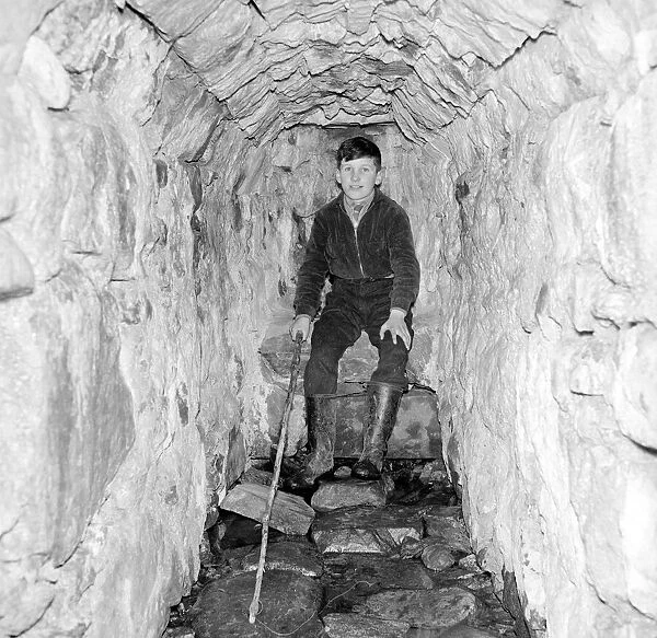 A young boy poses in the 'Well of Heads'at Invergarry, Scotland circa 1960