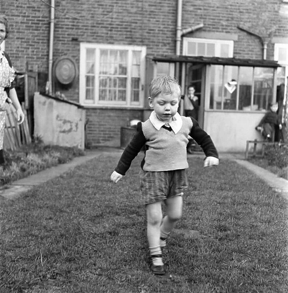 Young boy running in his back garden. October 1952 C5182