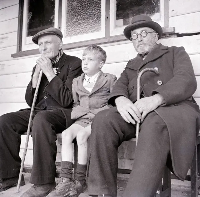 Framed Print : A young boy sits down with two old men on a bench. circa 1940