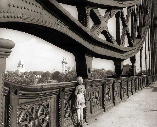 A young boy on tip toes to get a view from the bridge - 1959