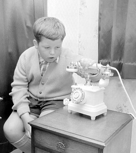 This young boy wait patiently for the telephone to ring. 20th June 1967