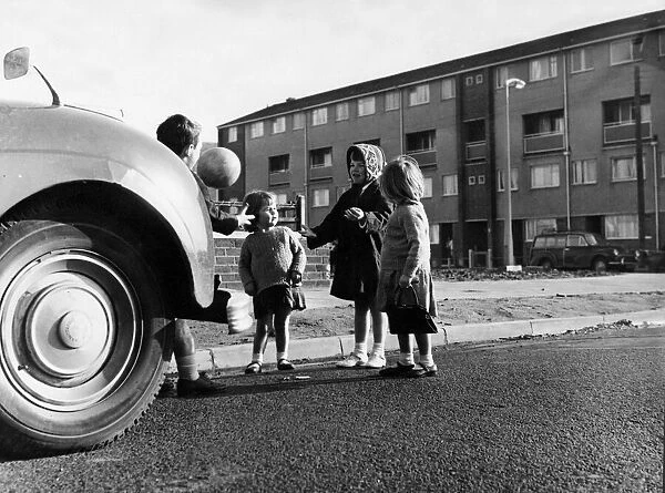 Young children of Halewood playing football in the streets among the parked cars