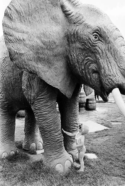 Young children playing between the legs of a model elephant statue at an adventure