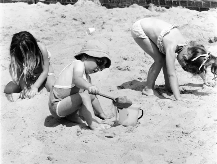 Framed Print : Young children playing in the sand, building sandcastles with a bucket