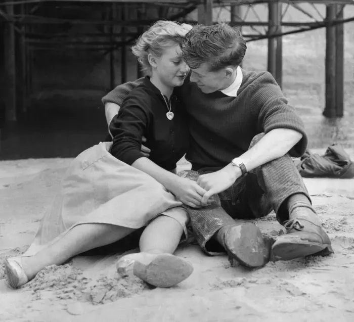 Framed Print : A young couple holding hands sitting on the beach Framed Print : A young couple holding hands sitting on the beach