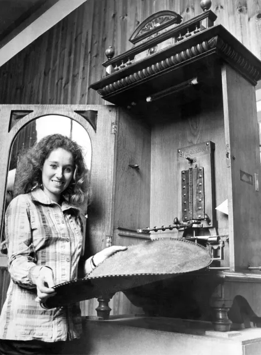 Framed Print : A young girl changes the disc on a vintage juke box or polyphone in September 1972