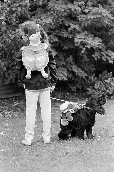 A young girl and a dog wearing a soft toy rucksack. 21st October 1986