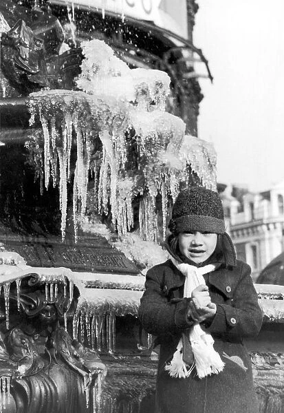 A young girl freezing cold, wrapped up in a coat, hat and scarf