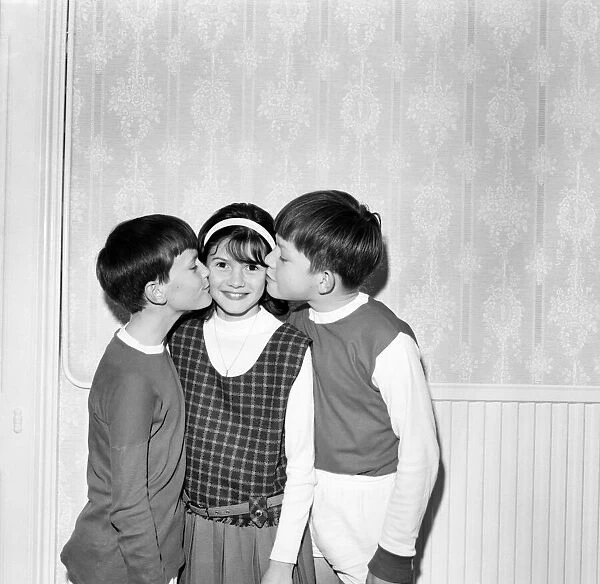 Young girl gets a kiss on each cheek from two boys. October 1969 Z10456-001