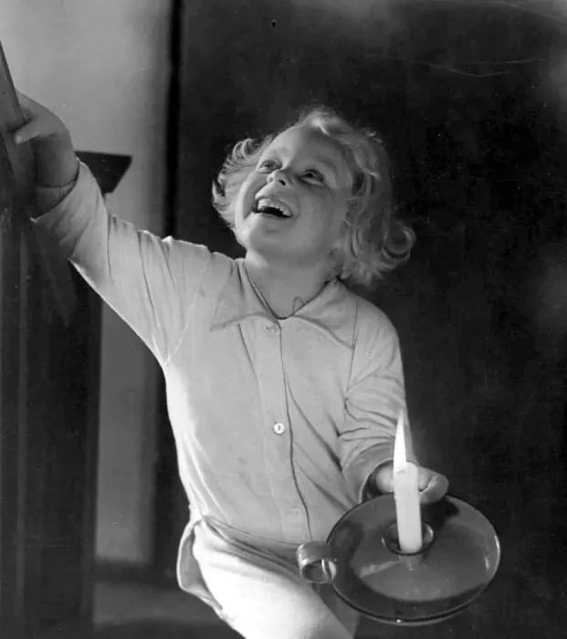 Framed Print : Young girl holding a candle as she climbs the stairs Circa 1945 P044499