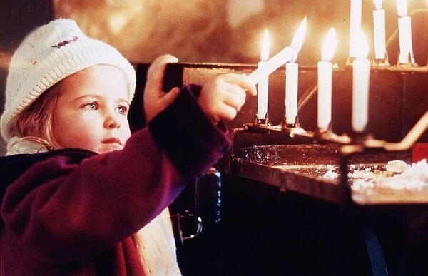 A young girl Katie Hughes Boyton lights a candle for peace at Westminster Cathedral at