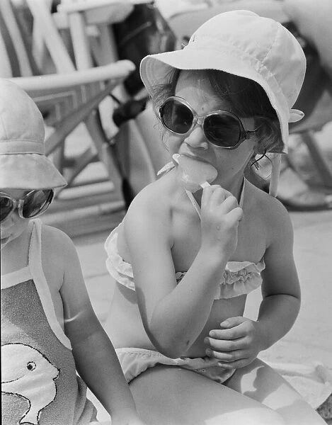 A young girl sitting on the beach, enjoying an ice lolly. 26th June 1979