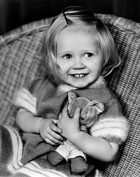 Young girl sitting in a wicker chair holding a teddy bear December 1969