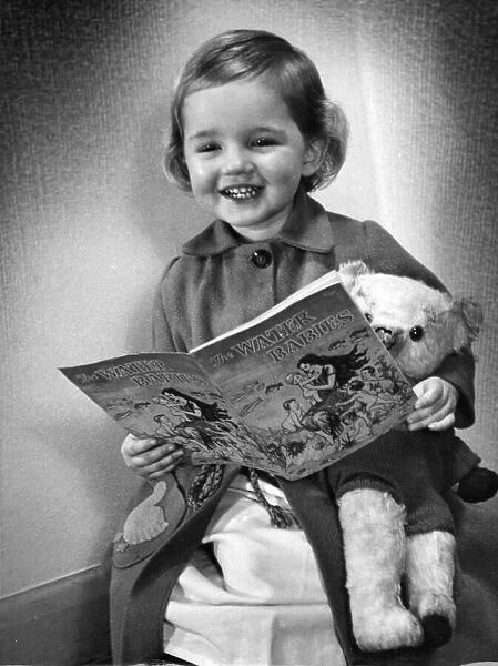 Young girl smiling as she reads her Water Baies book Circa 1945 P044490