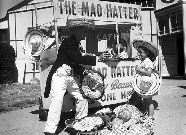 A young girl trying on a hat at The Mad Hatter stall, in Barry Island