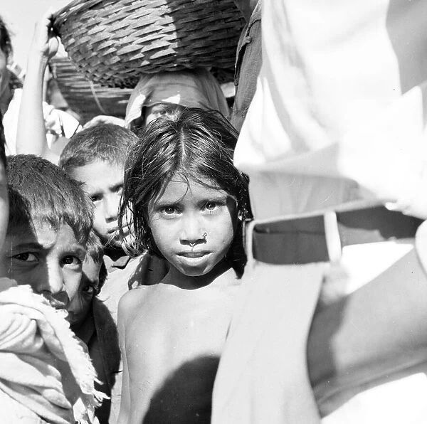 A young girl waits with her brothers and sister and the local traders wait to board a